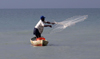 Belize - Seine Bight village: Garinagu / Garifuna man fishing - fisherman throwing a net from a canoe - pescador - photo by Charles Palacio