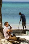 Cuba - Guardalavaca - beach - playing guitar and sweeping - photo by G.Friedman