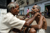 Calcutta / Kolkata, West Bengal, India: trimming a moustache - street barber working on the pavement - photo by G.Koelman