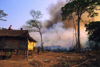 Laos: forest fire - a man is on the roof of his house with a bucket of water against the fire - photo by E.Petitalot