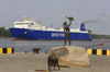 Klaipeda, Lithuania: bronze sculpture of a boy and dog meeting ships - a ferry enters the harbour - Tor Maxima - photo by A.Dnieprowsky