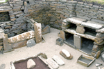 Orkney island - Skara Brae - View of House #1 - from right to left are the stone dresser where prizeobjects were stored and displayed, a box bed, lower center is the hearth,and in front of the dresser are containers for preparing fish bait - photo by Carlton McEachern