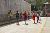 A group of african american kids run on a cobblestone side street, participating on a spoon and egg race. Portobello, Coln, Panama, Central America - photo by H.Olarte