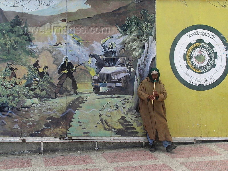 algeria110: Algeria / Algerie - Bou Saada: playing flute in front of billboard celebrating the Algerian war - photo by J.Kaman - musicien devant panneau-réclame célébrant la guerre algérienne - (c) Travel-Images.com - Stock Photography agency - Image Bank