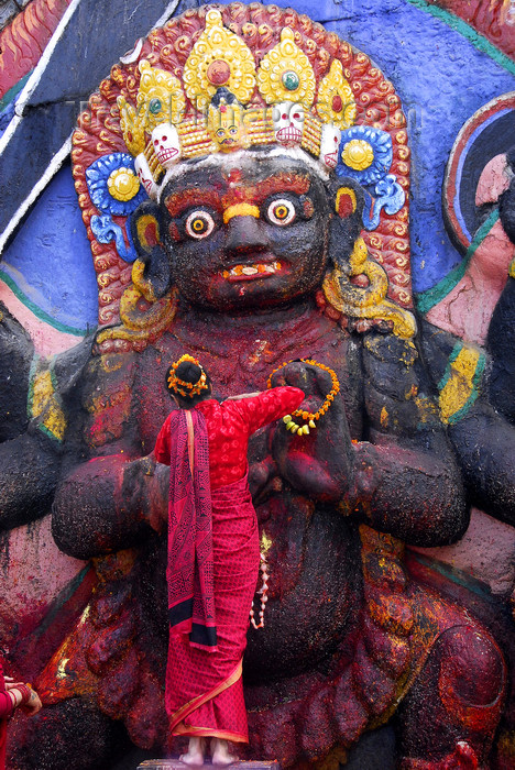 nepal217: Kathmandu, Nepal: woman making offering to Kala Bhairab statue in Durbar square - 17th century stone image - photo by J.Pemberton - (c) Travel-Images.com - Stock Photography agency - Image Bank