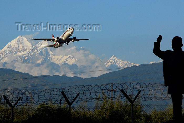 nepal223: Kathmandu valley, Nepal: Tribhuvan International Airport - plane taking off with Himalayas behind - man waving outside razor wire fence - photo by J.Pemberton - (c) Travel-Images.com - Stock Photography agency - Image Bank