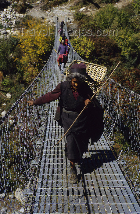 nepal338: Annapurna area, Nepal: woman with bamboo basket crossing a suspension bridge - photo by W.Allgöwer - (c) Travel-Images.com - Stock Photography agency - Image Bank
