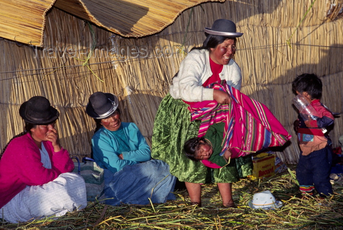 peru110: Lake Titicaca, Puno department, Peru: Aymara woman hoists baby at a wedding celebration on the main floating island - women with typical hats - photo by C.Lovell - (c) Travel-Images.com - Stock Photography agency - Image Bank