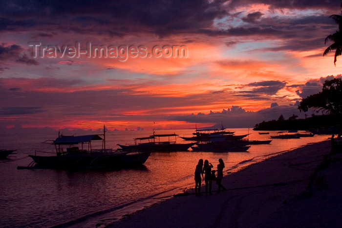 phil54: Alona Beach, Bohol island, Central Visayas, Philippines: local Banca on the beach in vivid colors - people watch the red skies - photo by S.Egeberg - (c) Travel-Images.com - Stock Photography agency - Image Bank