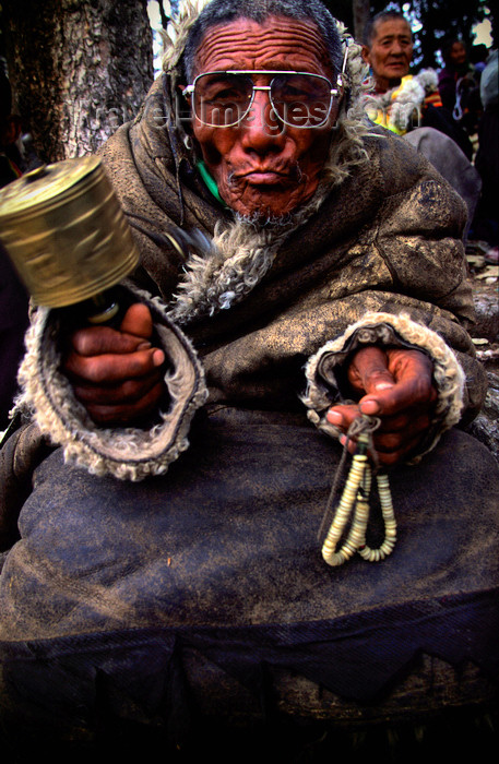 tibet103: Lhasa, Tibet - pilgrims worshipping - elderly man with prayer wheel and beads - photo by Y.Xu - (c) Travel-Images.com - Stock Photography agency - Image Bank