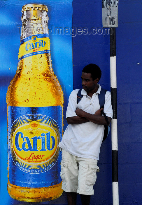 trinidad-tobago41: Scarborough, Tobago: man waiting for a bus in front of a drink advertising - Carib lager - photo by E.Petitalot - (c) Travel-Images.com - Stock Photography agency - Image Bank