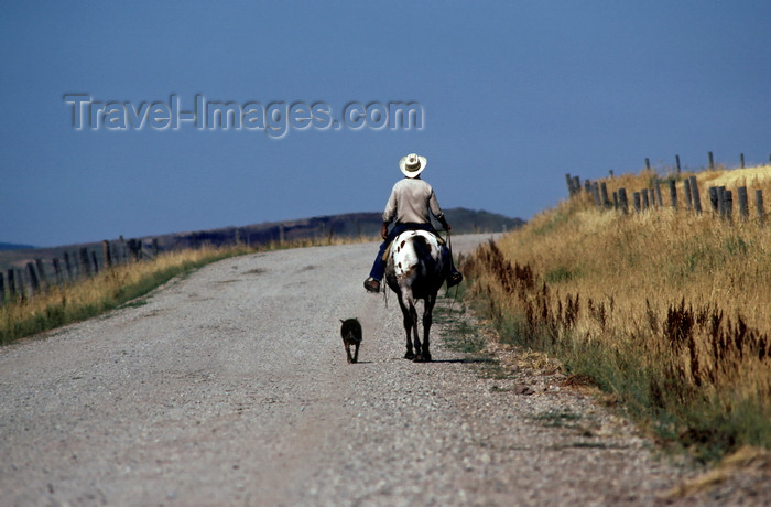 usa1248: Wyoming, USA: cowboy riding his horse down the road with his dog by his side - photo by C.Lovell - (c) Travel-Images.com - Stock Photography agency - Image Bank