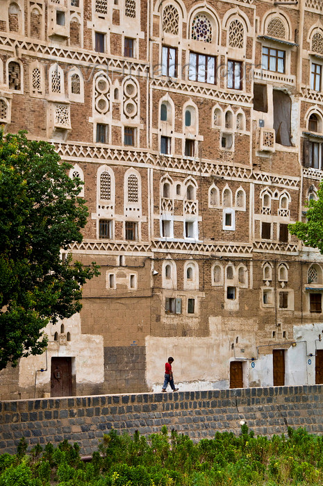 yemen50: Sana'a / Sanaa, Yemen: child walking along wall in front of Old City houses - ancient skyscrapers - UNESCO World Heritage Site - houses with elaborate exterior ornamentation - photo by J.Pemberton - (c) Travel-Images.com - Stock Photography agency - Image Bank