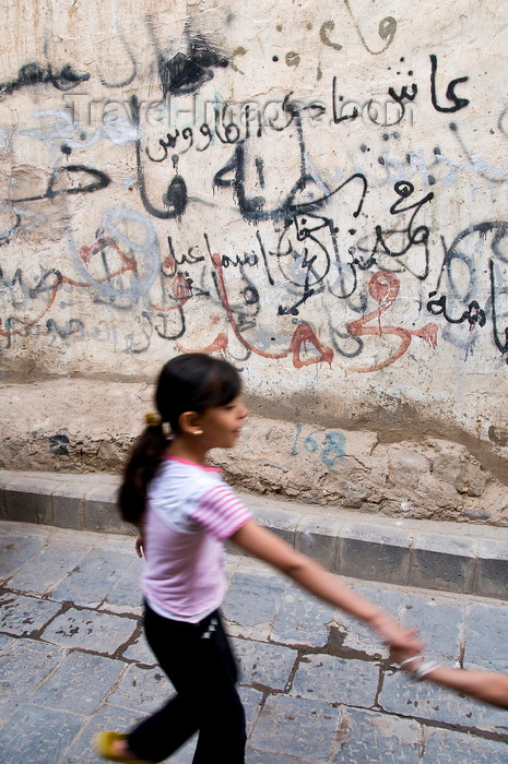 yemen51: Sana'a / Sanaa, Yemen: girl in front of graffitied wall - Arabic characters - photo by J.Pemberton - (c) Travel-Images.com - Stock Photography agency - Image Bank