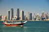 Doha / Ad Dawhah, Qatar: water taxi dhow on Doha bay and West Bay skyline from the south side of Doha Bay - photo by M.Torres