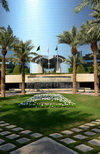 Riyadh, Saudi Arabia: Kingdom Centre skyscraper - garden with a waterfall, flowers in the shape of the tower and palm trees - view from Street 94 - photo by M.Torres