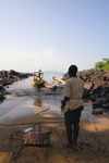 Kent, Freetown Peninsula, Sierra Leone: boat taxi - client with luggage waits on the beach - photo by J.Britt-Green